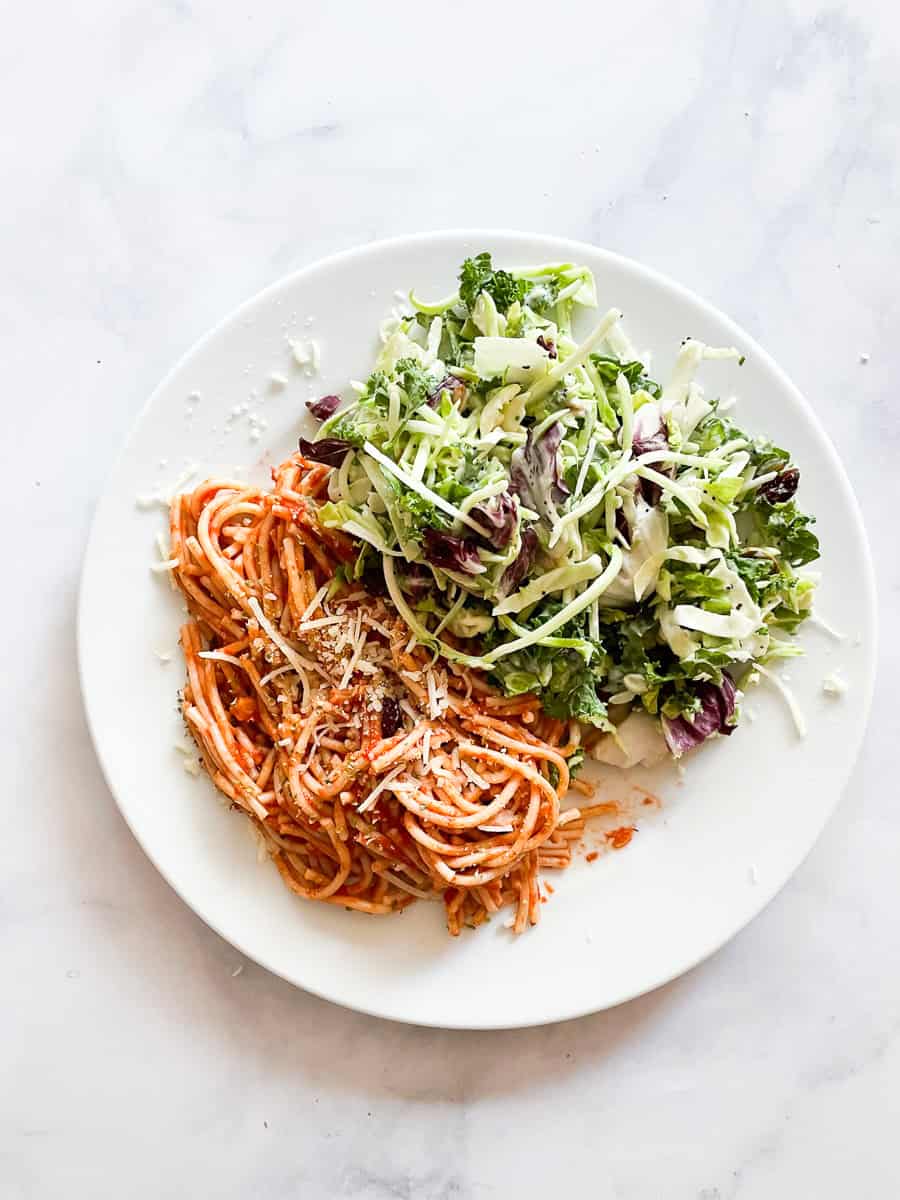 A plate of spaghetti with super simple tomato sauce and a side of salad.