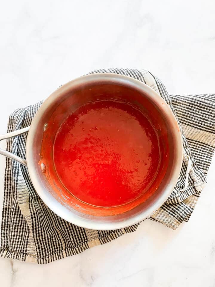 Pureed tomatoes are added to a pot of tomato sauce.