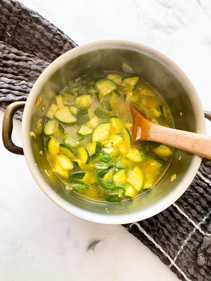 Basil is added to the soup pot.