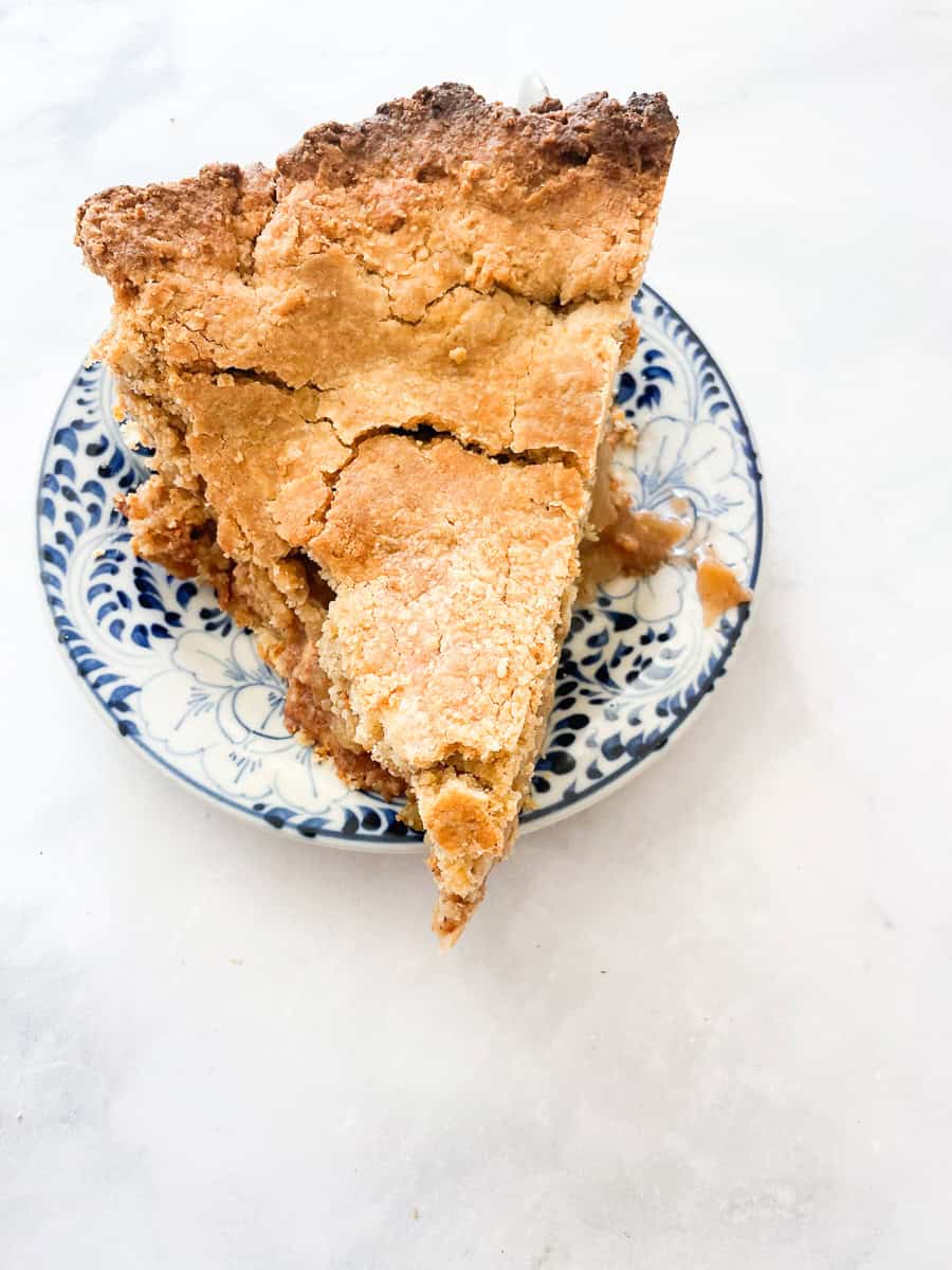 A piece slice of gluten free apple pie on a blue and white plate.