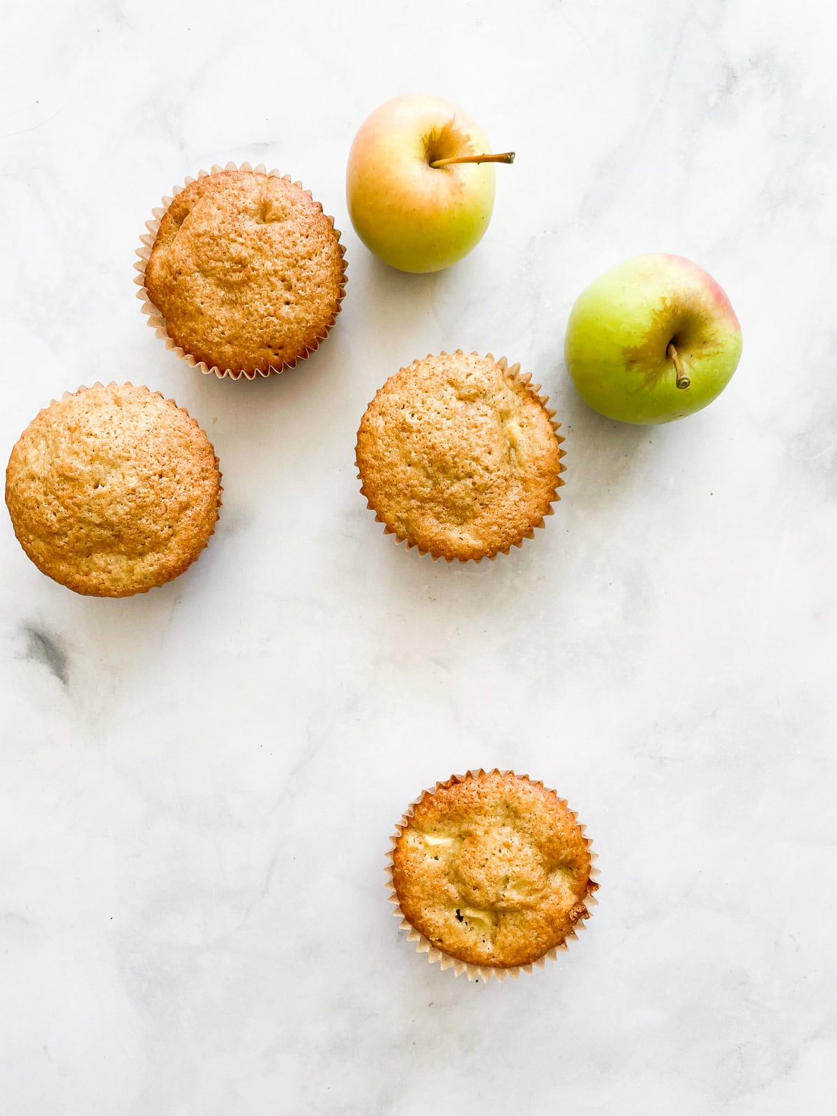 Four gluten free apple muffins with apples.