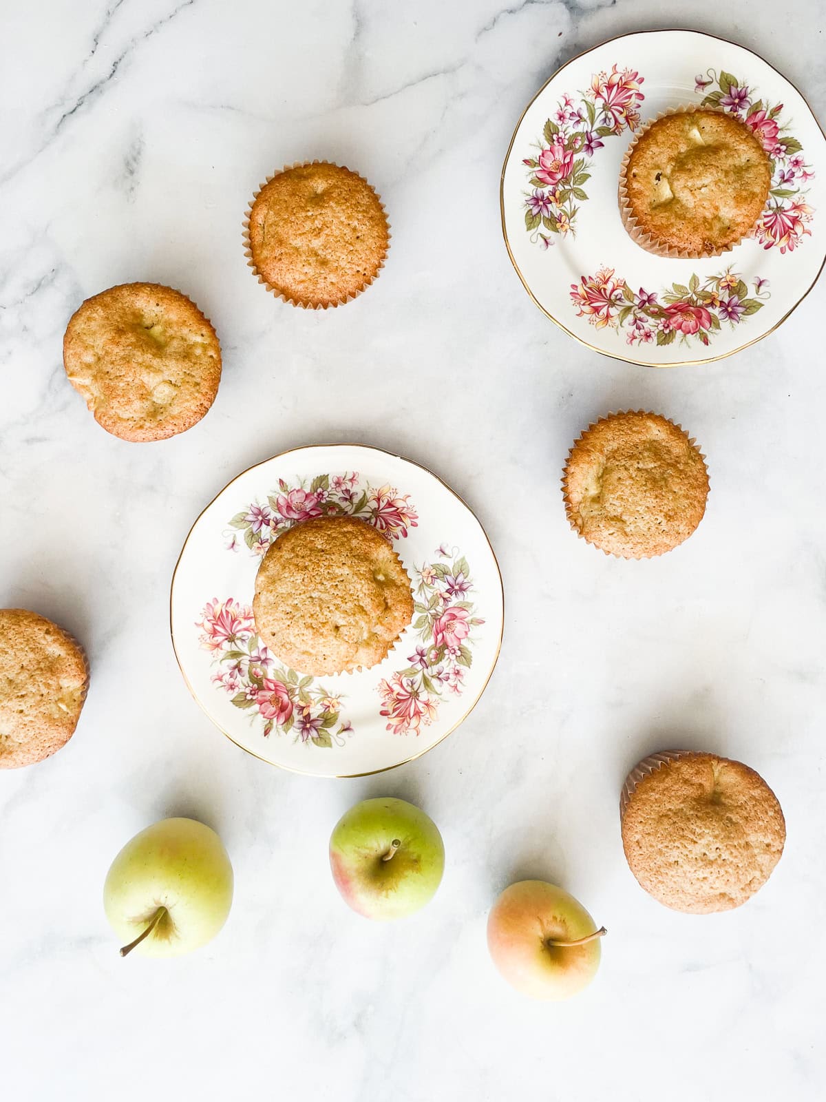 Apple muffins on plates with apples.