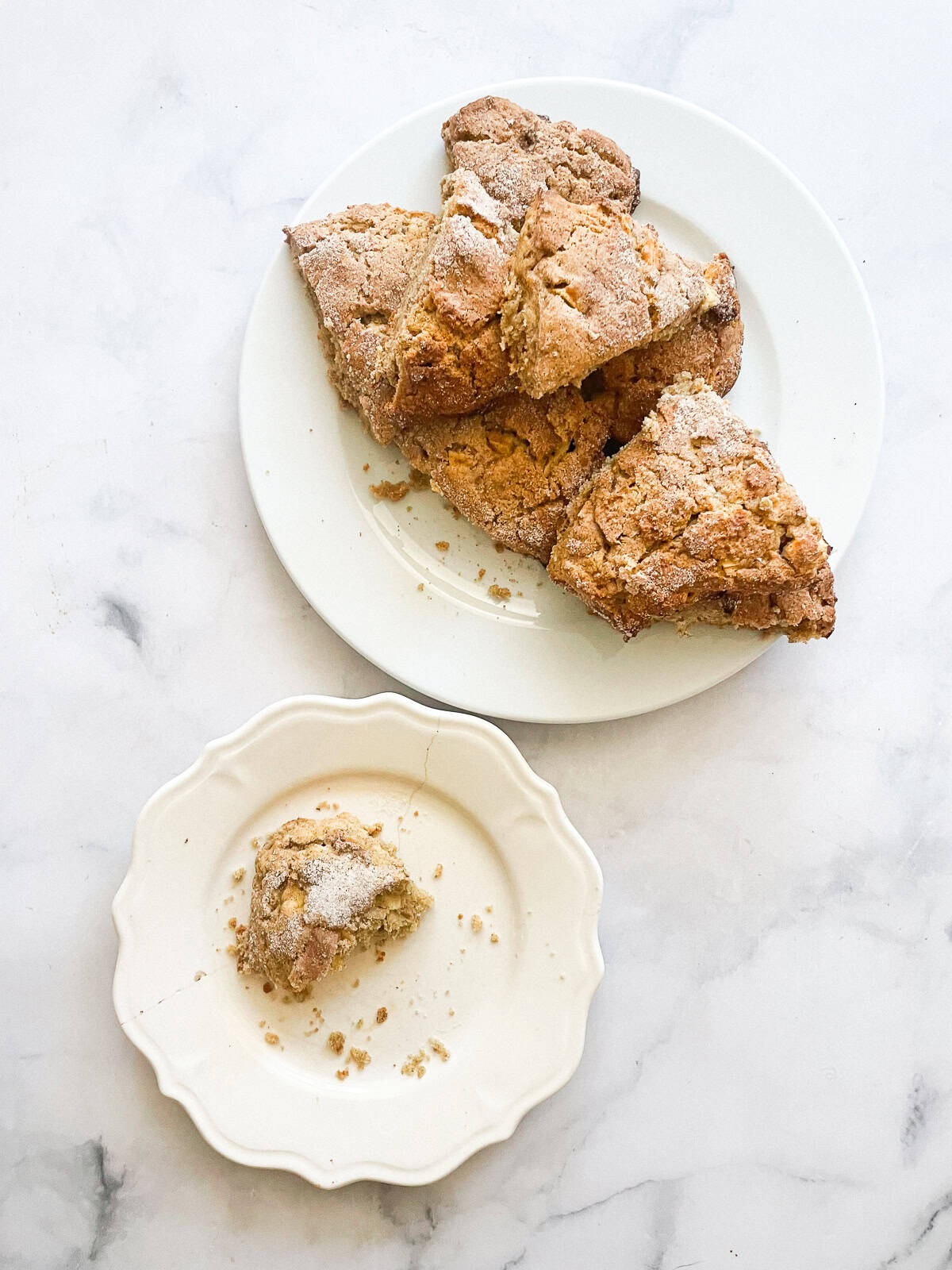 A pile of apple scones on a plate with a scone on a plate.