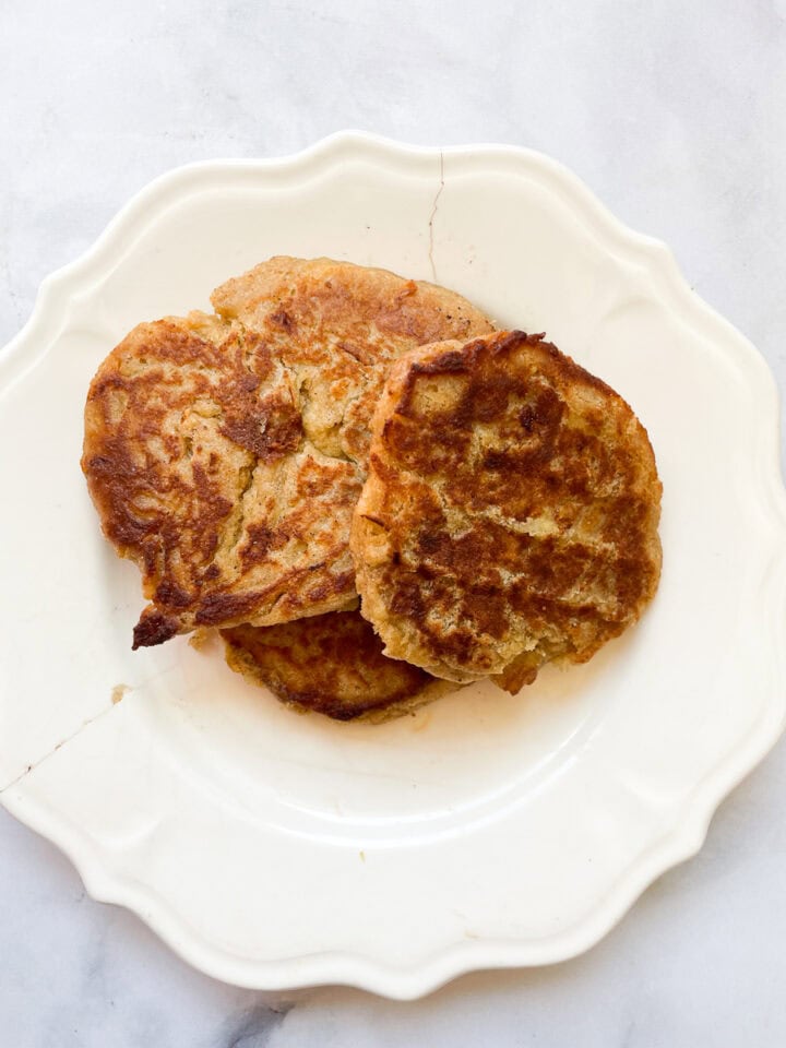 Gluten free banana buttermilk pancakes stacked on a white plate.