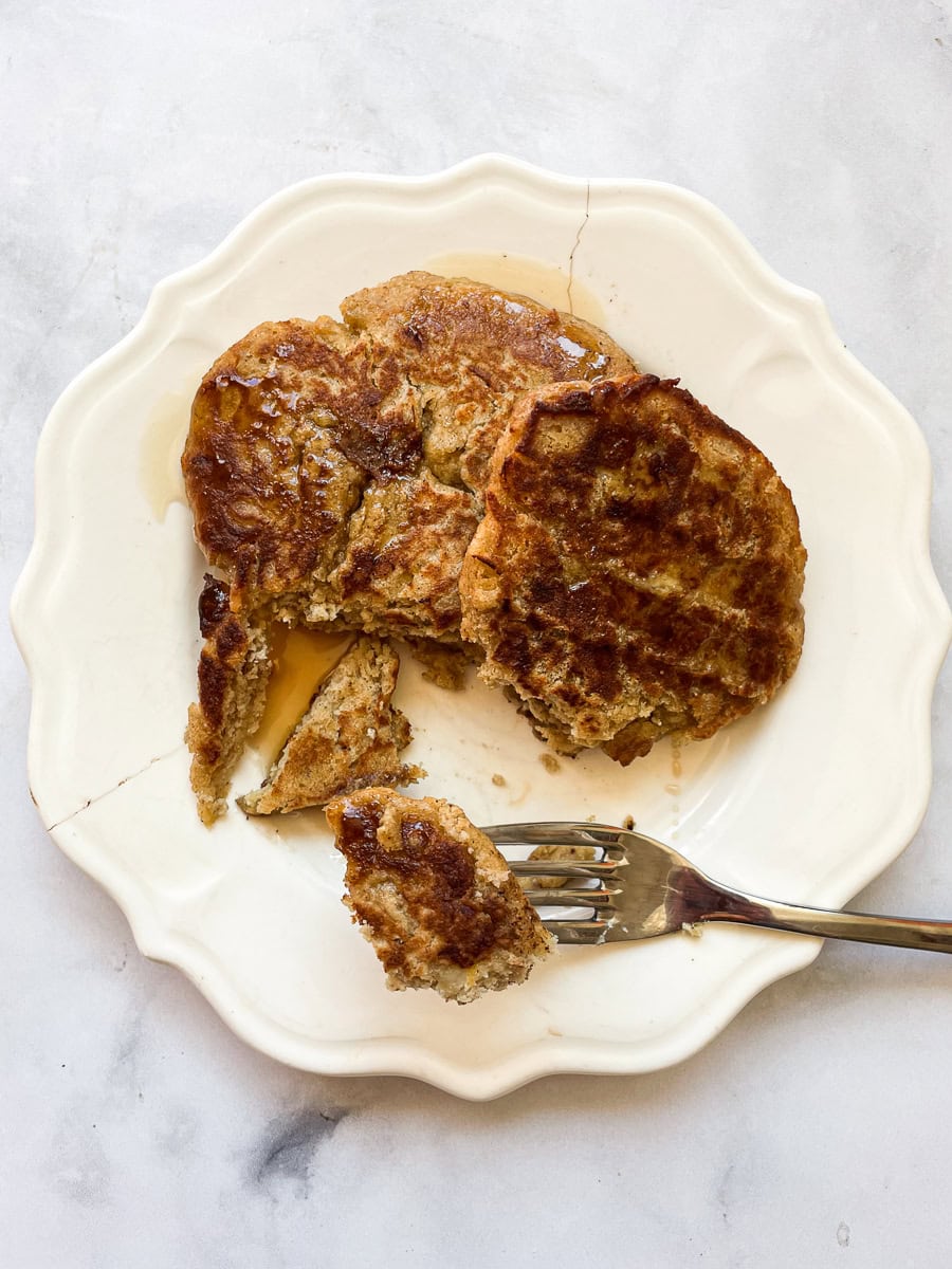 A fork cuts into a stack of gluten free banana buttermilk pancakes.