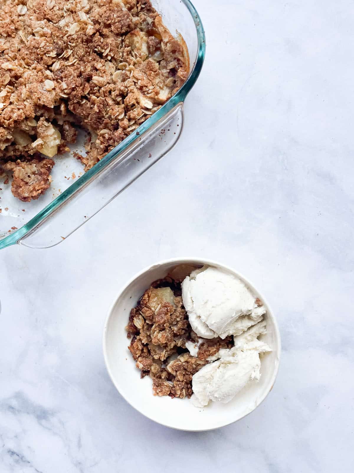 A pan of oatmeal apple crisp with a bowl of crisp.