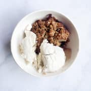 A bowl of apple crisp with ice cream.