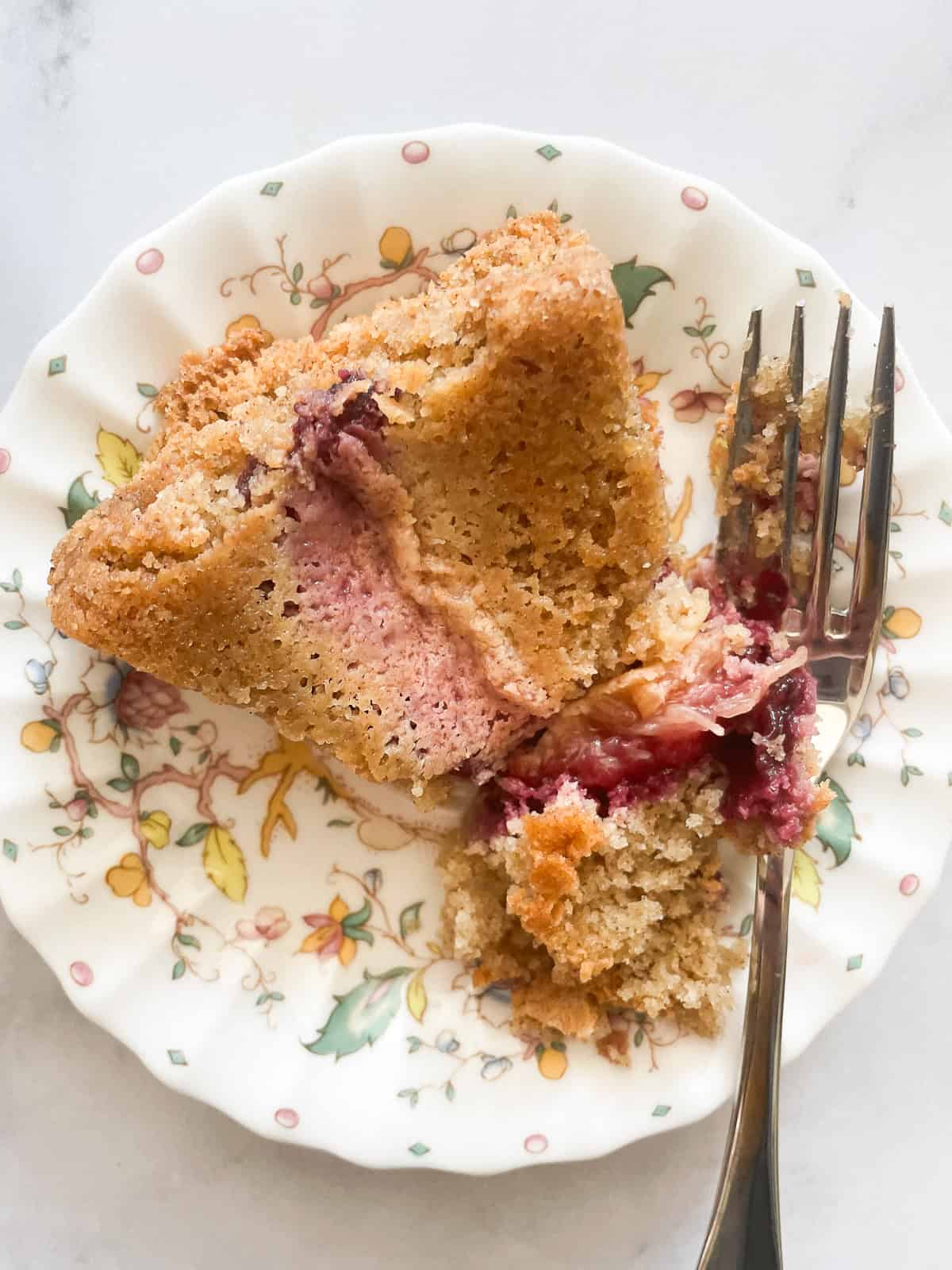 A fork alongside a piece of plum torte on a plate.