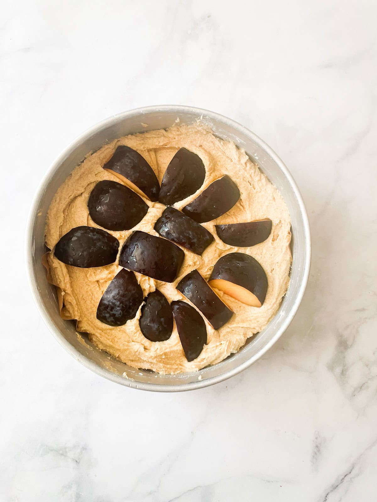 Sliced plums are added to plum torte batter.