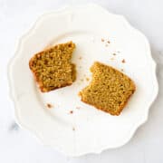 Two halves of a slice of pumpkin bread on a plate.