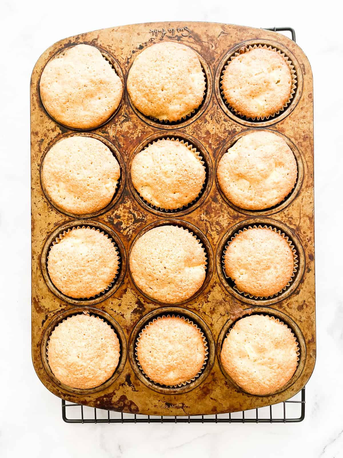 Apple muffins cool in a tin.