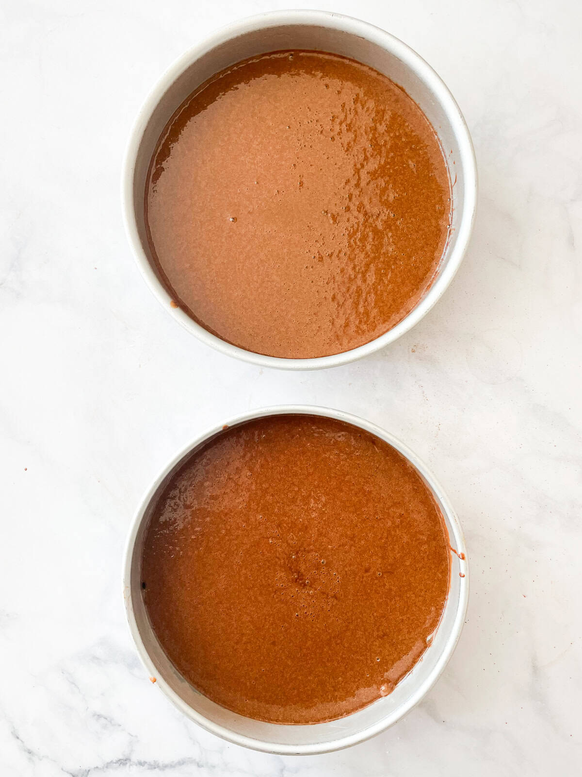 Gluten free chocolate layer cake batter in pans.