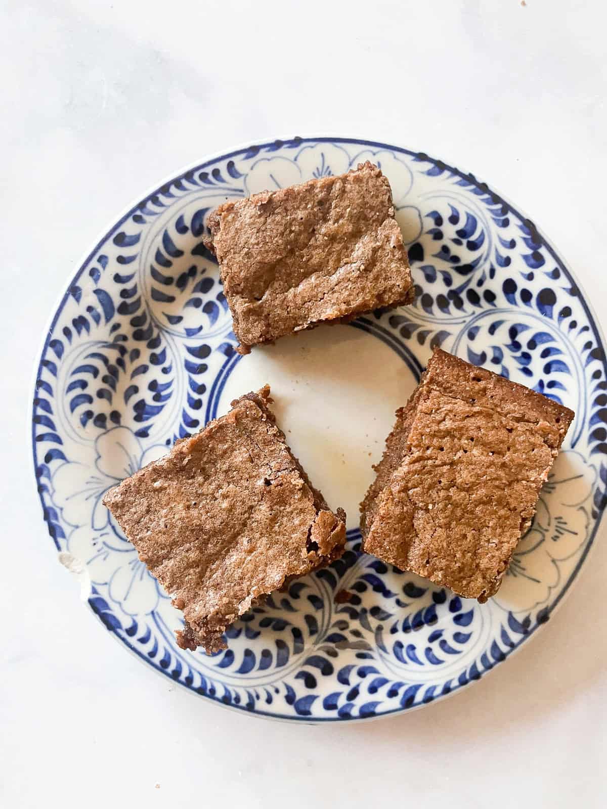 Three whole wheat brownies on a blue and white plate.