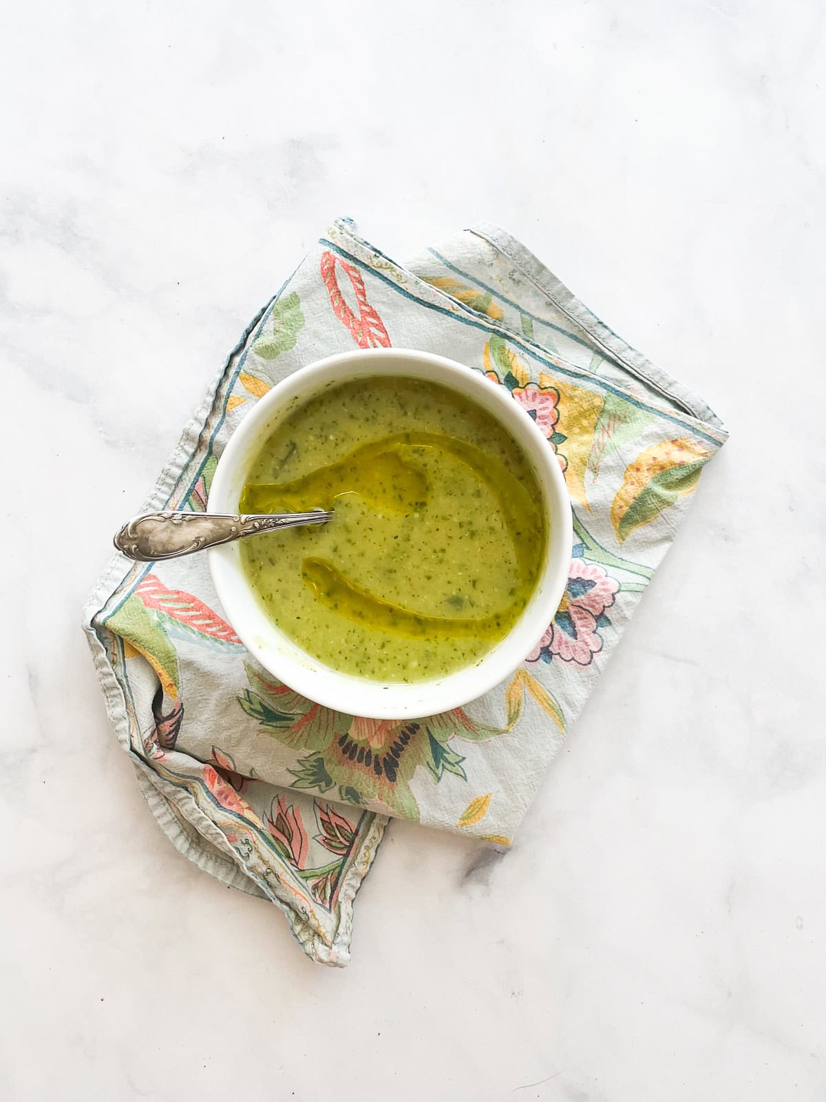 A bowl of zucchini soup on a blue napkin.