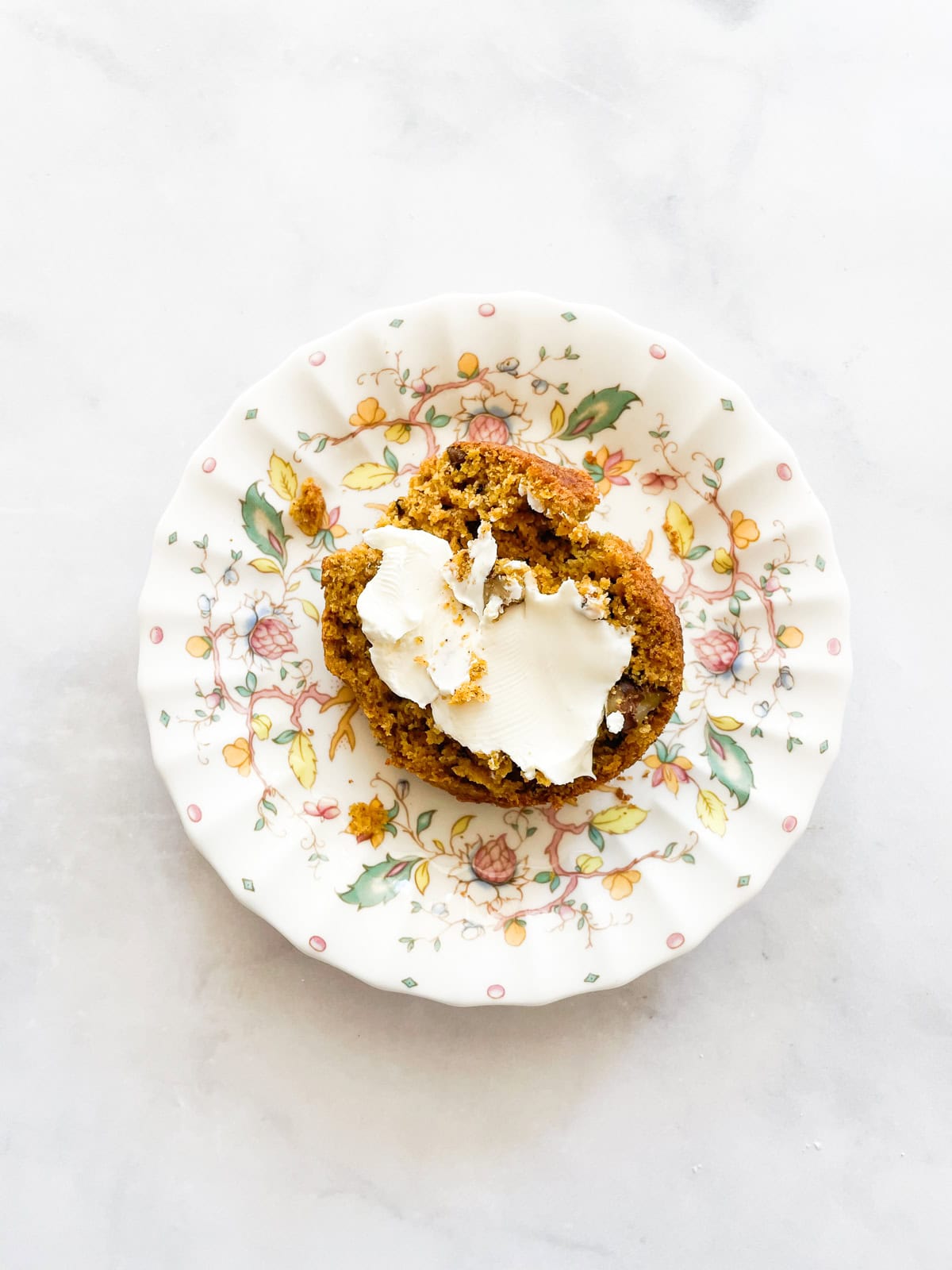 Cream cheese on half of a pumpkin banana muffin.