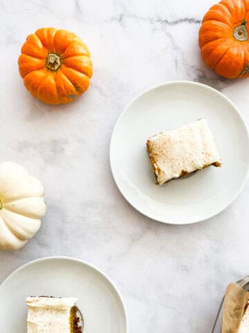 Two gluten free pumpkin bars on plates with mini pumpkins.