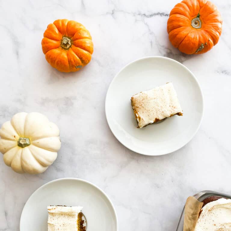 Two gluten free pumpkin bars on plates with mini pumpkins.