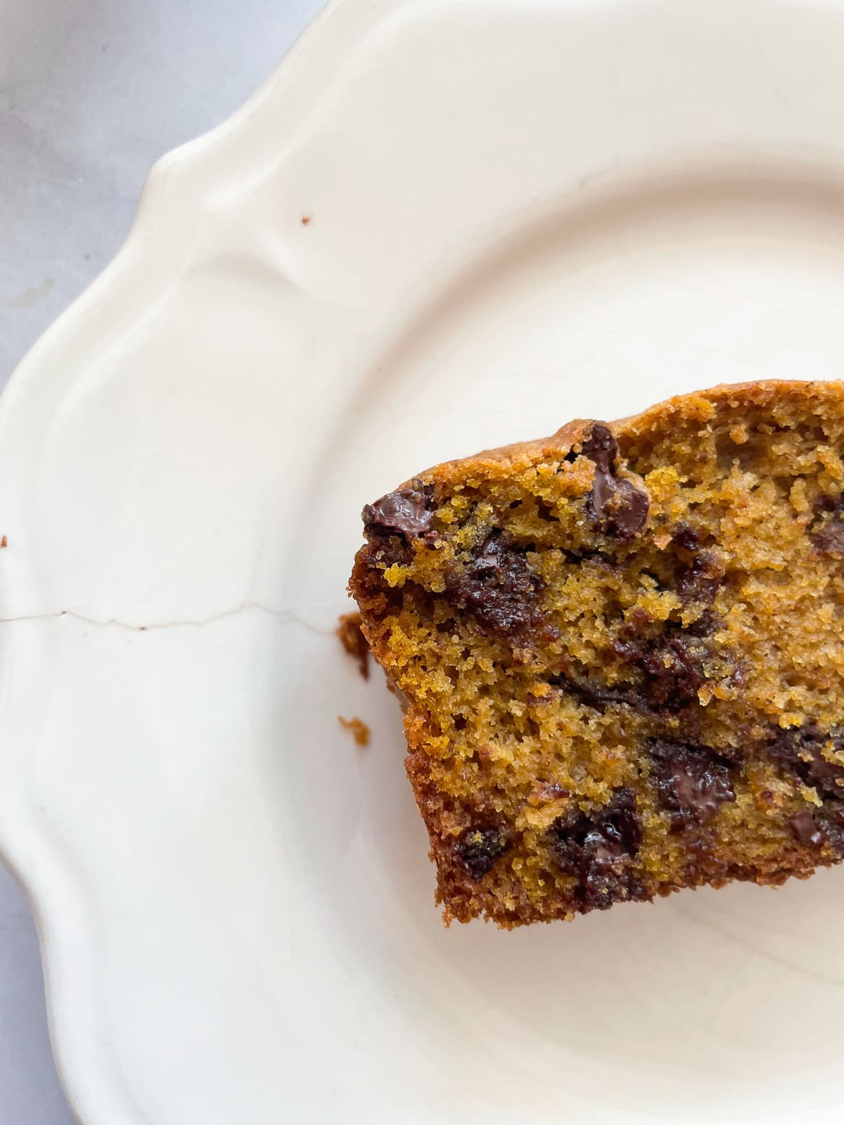 Half of a piece of pumpkin chocolate chip bread on a plate.