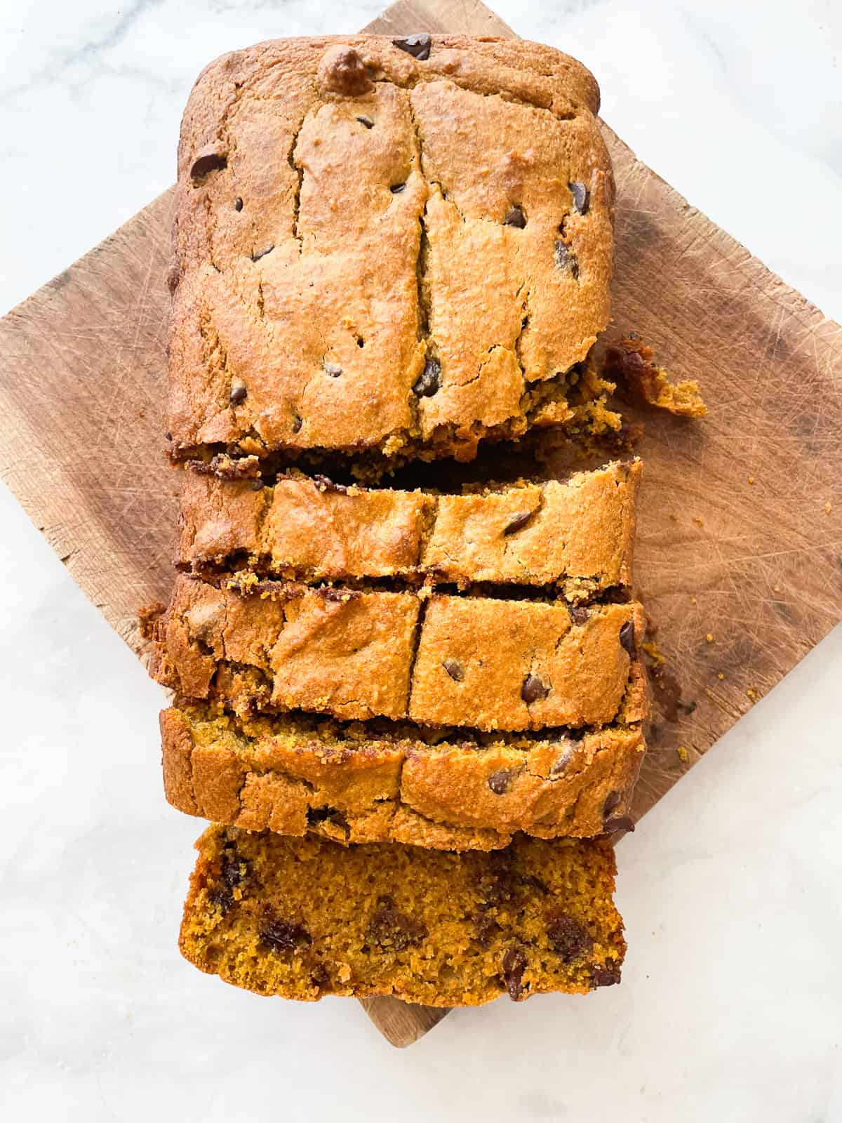 A cutting board with a sliced loaf of pumpkin chocolate chip bread.