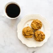 A plate of gluten free pumpkin chocolate chip muffins and a cup of coffee.