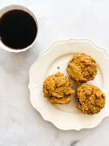 A plate of gluten free pumpkin chocolate chip muffins and a cup of coffee.