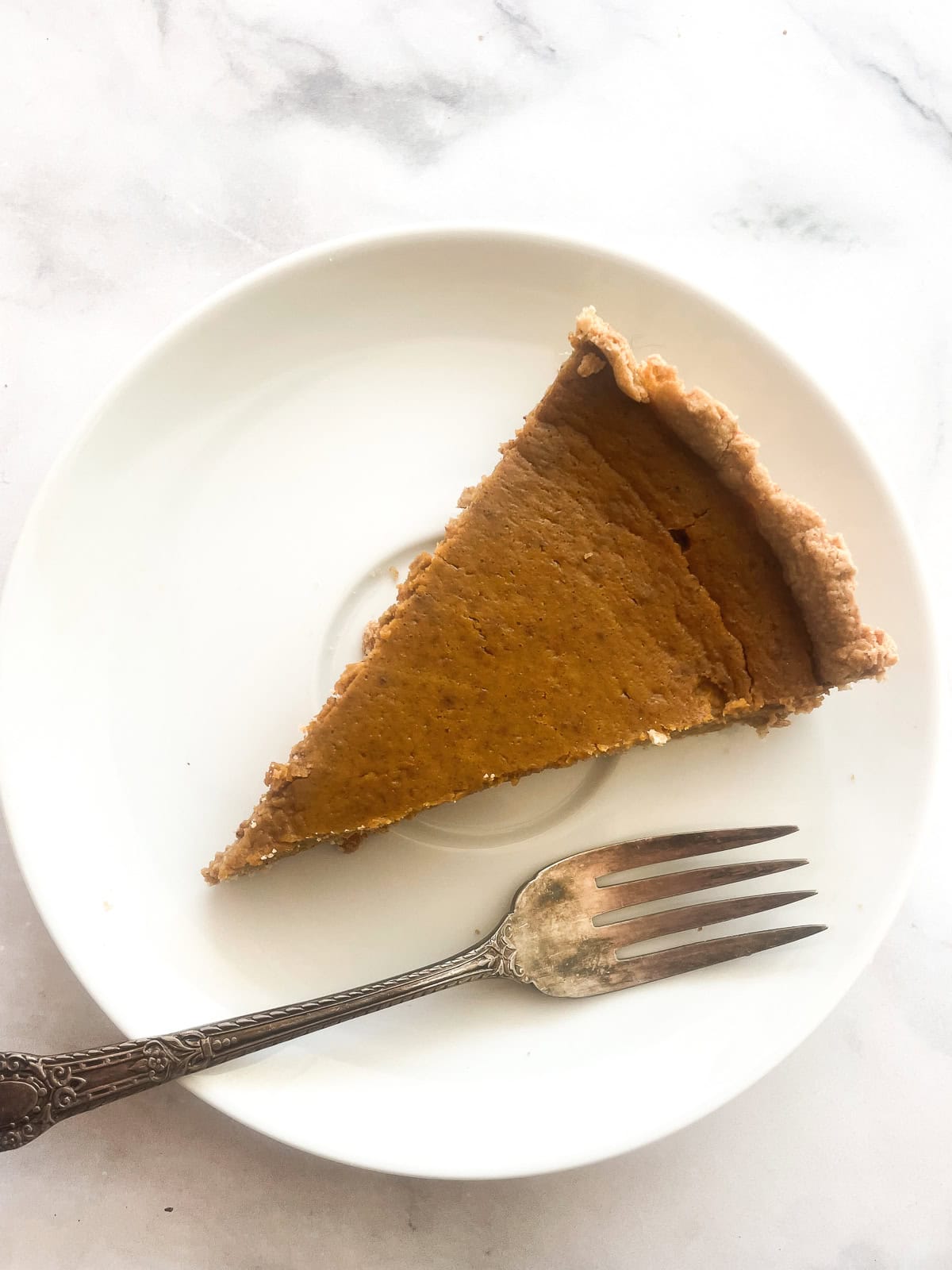 A slice of gluten free pumpkin pie on a plate with a fork.