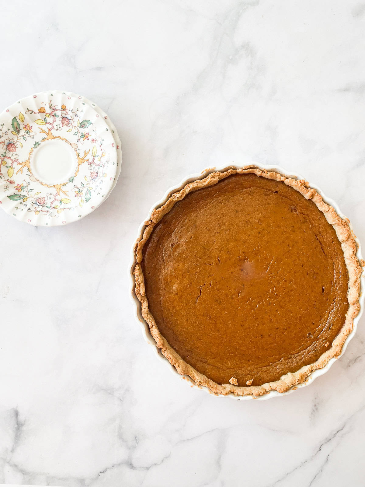 A gluten free pumpkin pie and a stack of plates.