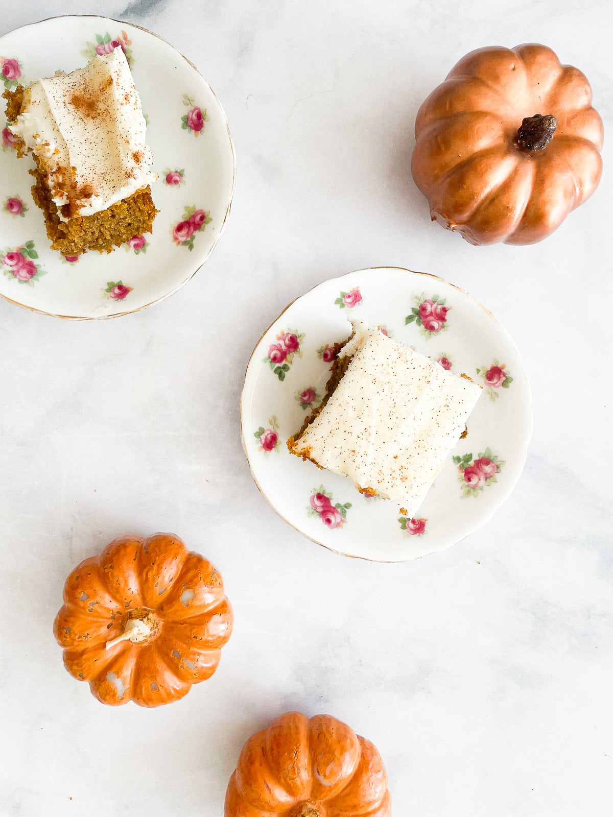 Two small pumpkin candles next to slices of pumpkin sheet cake.