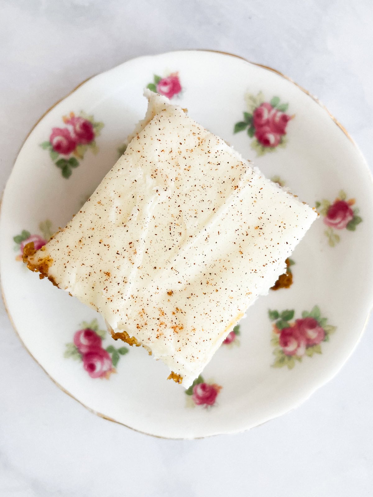 A square of pumpkin sheet cake on a flowered plate.