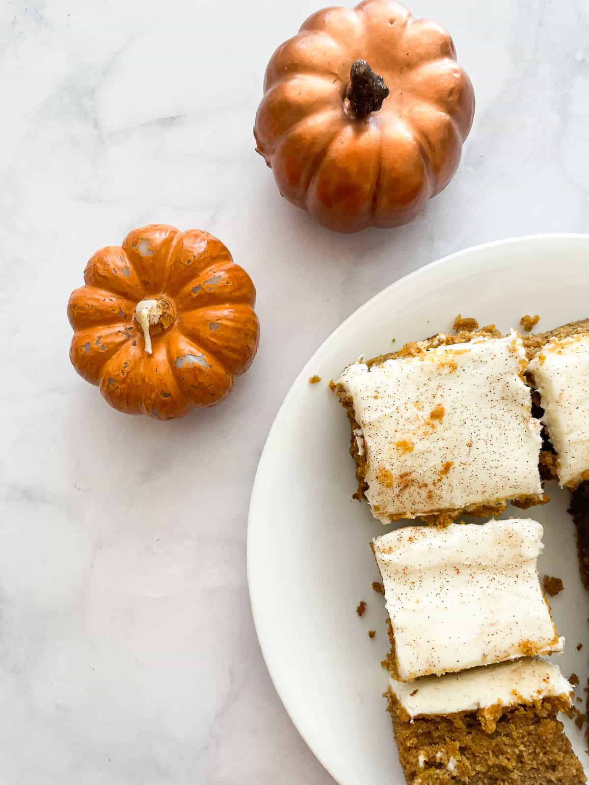 Mini pumpkin candles next to slices of pumpkin sheet cake.