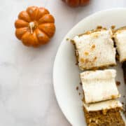 Mini pumpkin candles next to slices of pumpkin sheet cake.