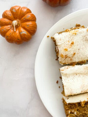 Mini pumpkin candles next to slices of pumpkin sheet cake.