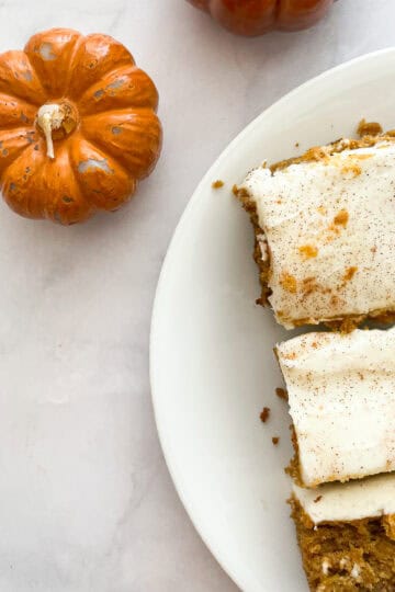 Mini pumpkin candles next to slices of pumpkin sheet cake.