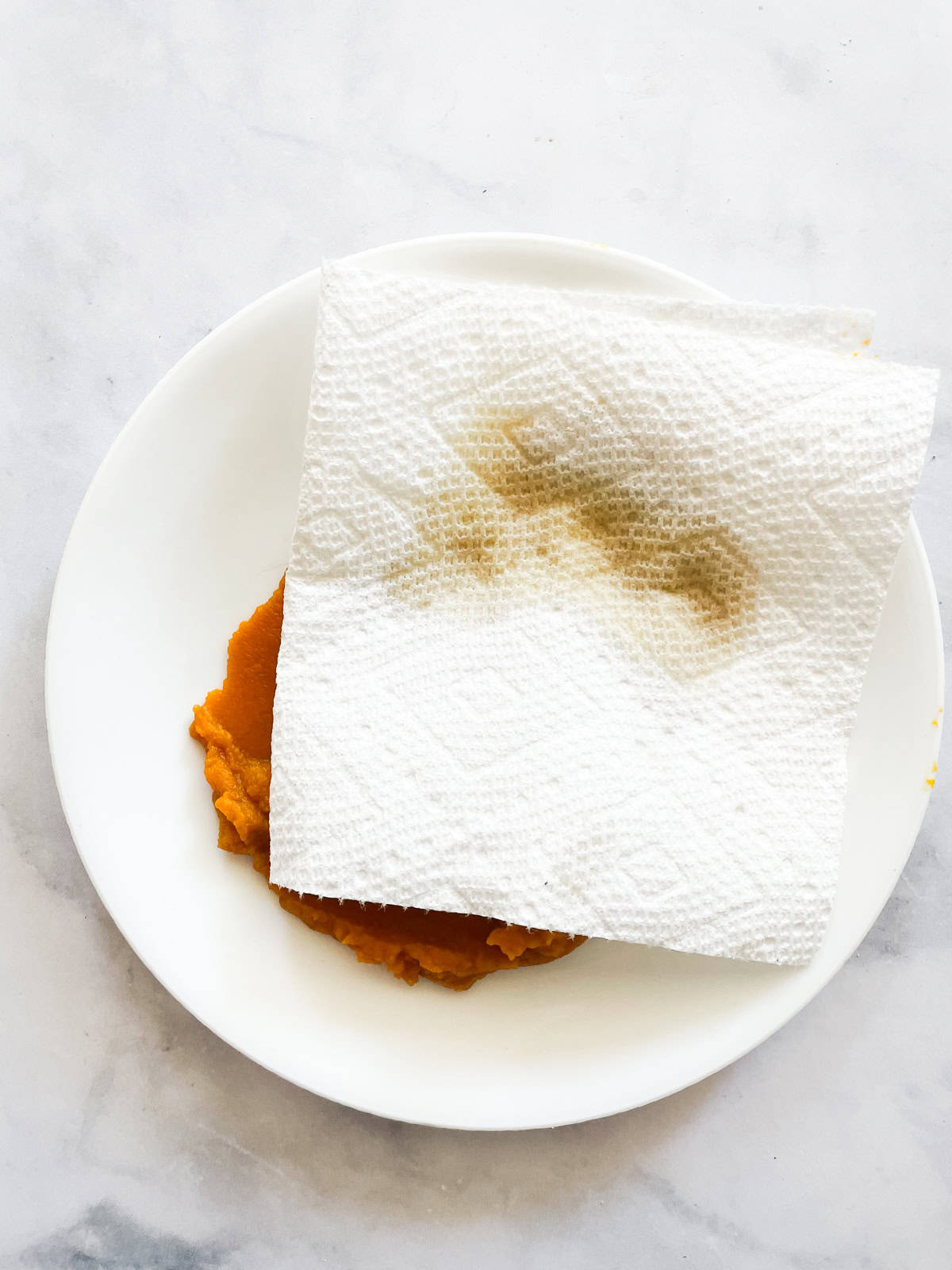 A paper towel blots water from a plate of pumpkin.