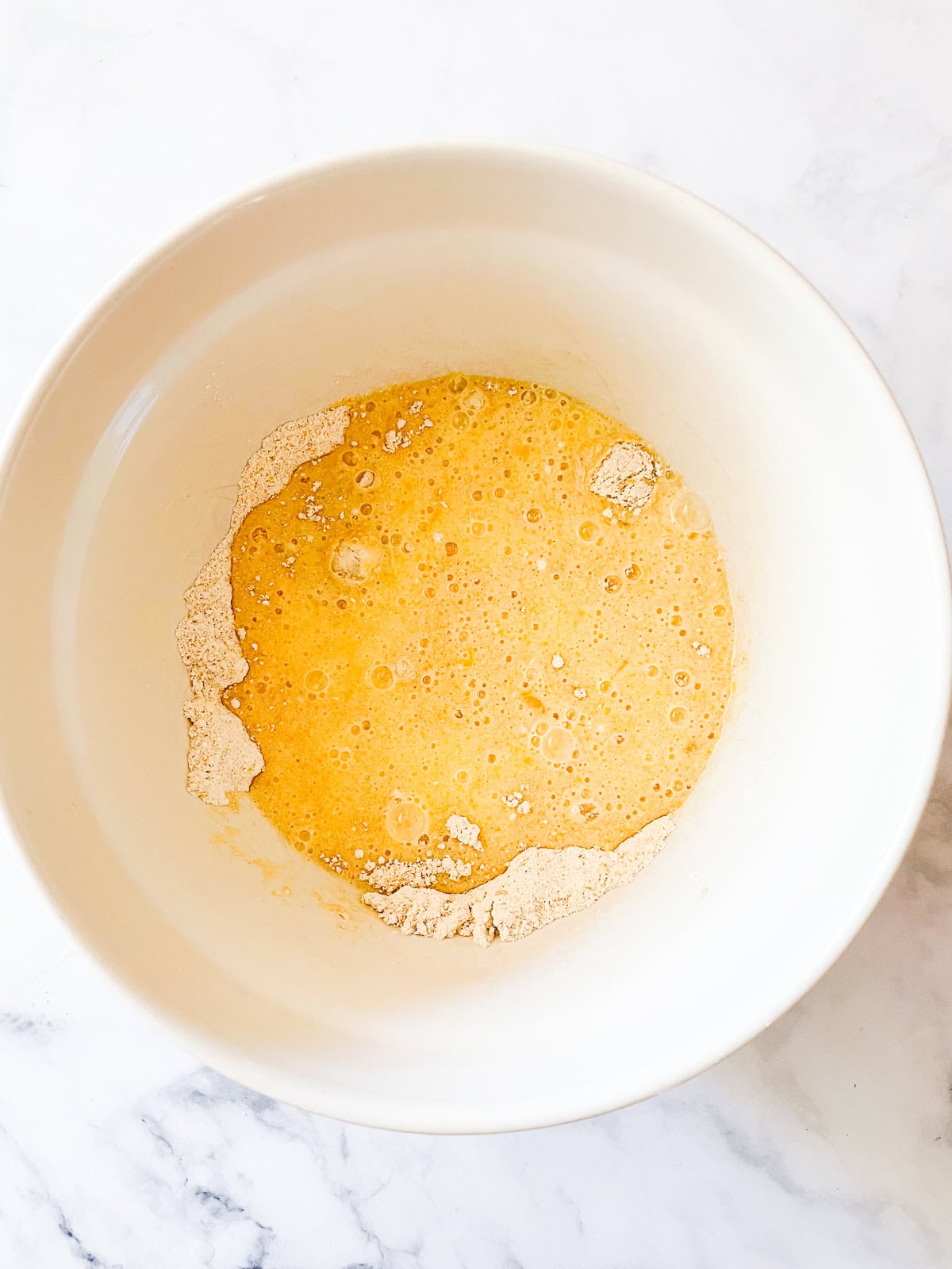 Wet and dry mixes for cornbread are combined in a bowl.