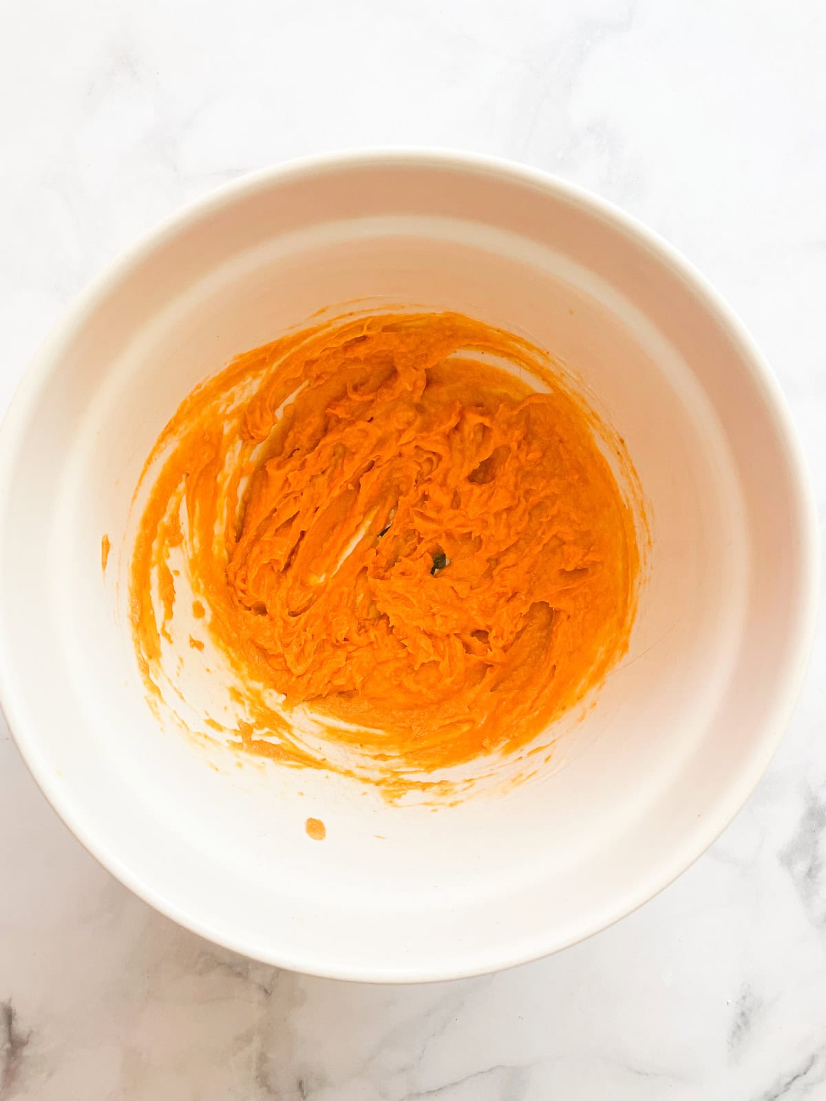 Pumpkin puree mixed with egg and butter in a bowl.