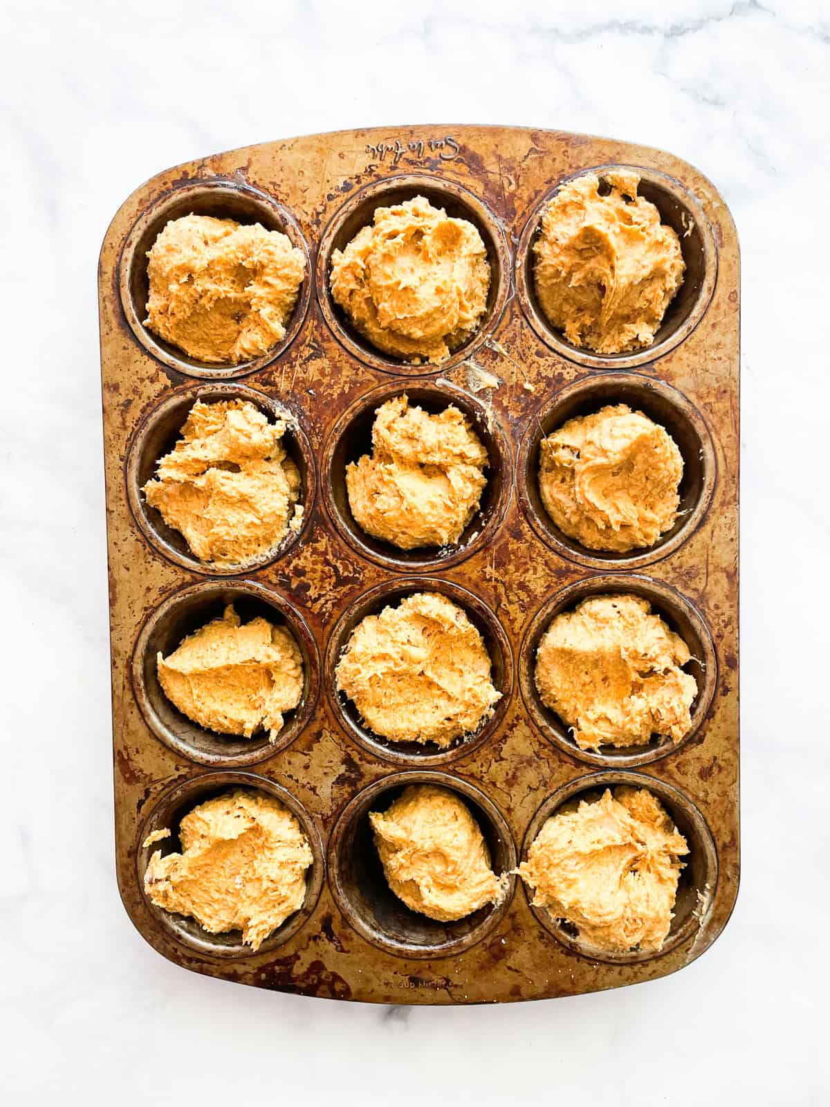 Gluten free pumpkin banana muffin batter in a tin.