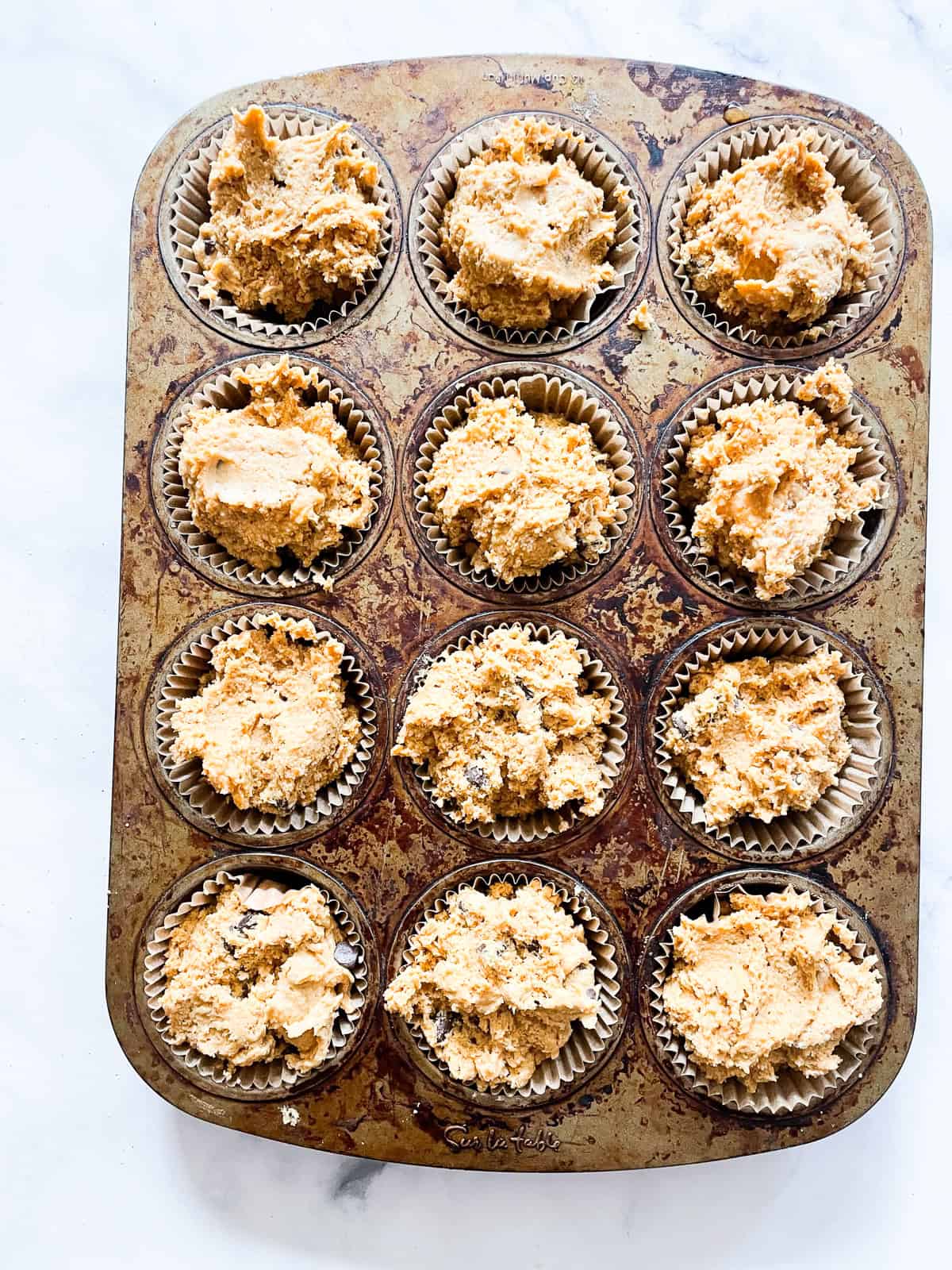 Pumpkin chocolate chip muffins batter in a muffin pan.