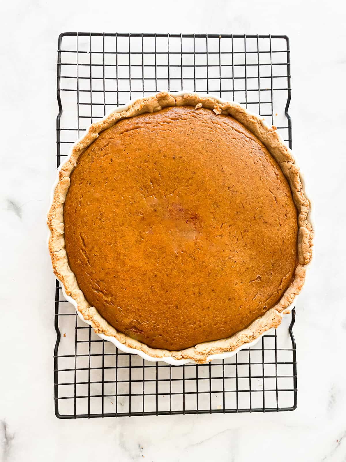 A gluten free pumpkin pie cools on a rack.