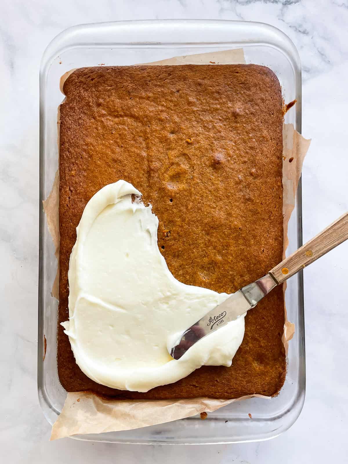 Cream cheese frosting is spread on the pumpkin sheet cake.