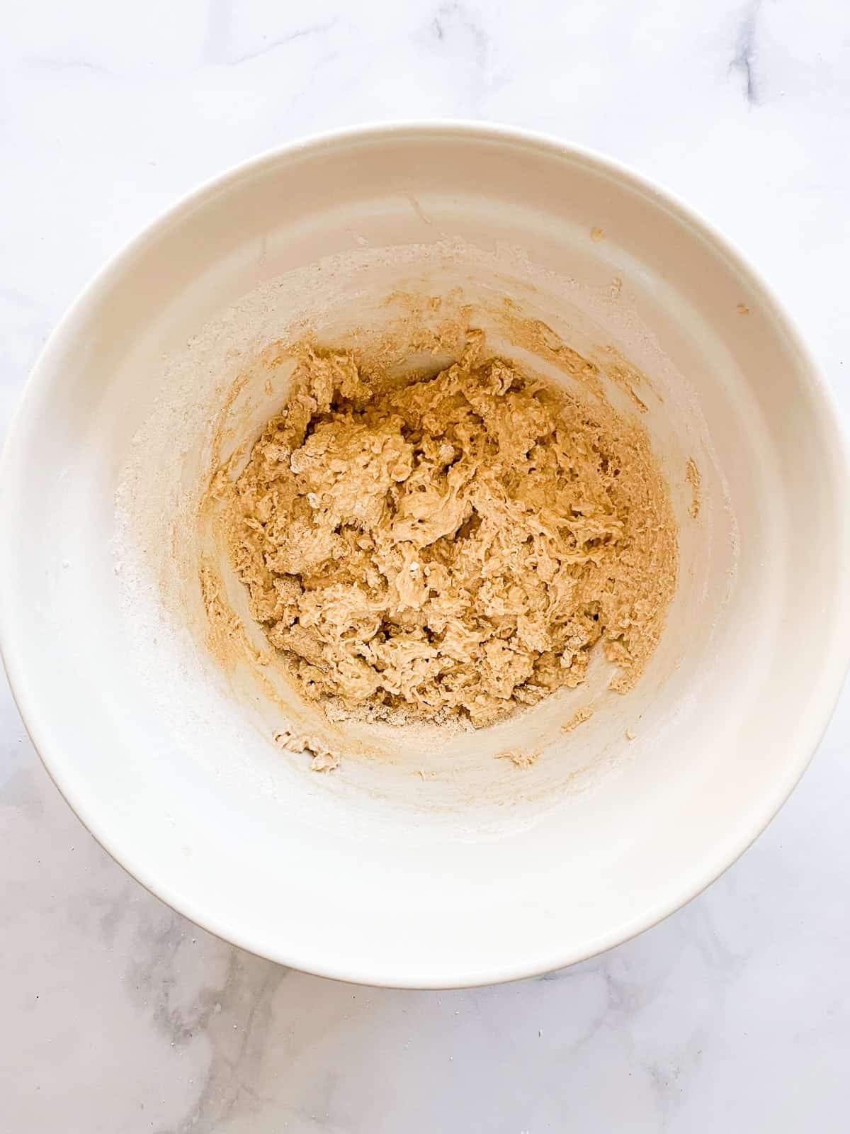 Flour is added to a bowl of leftover oatmeal muffins batter.