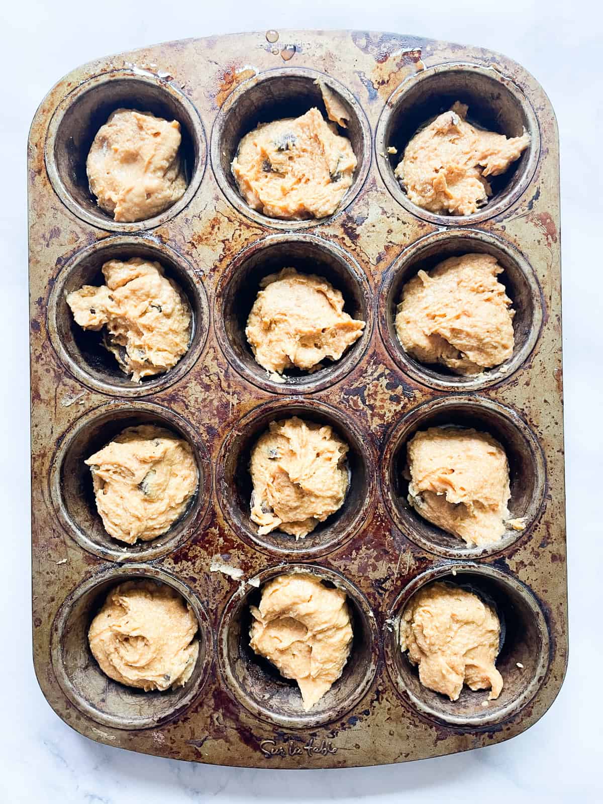 Oat flour pumpkin muffin batter in a muffin tin.