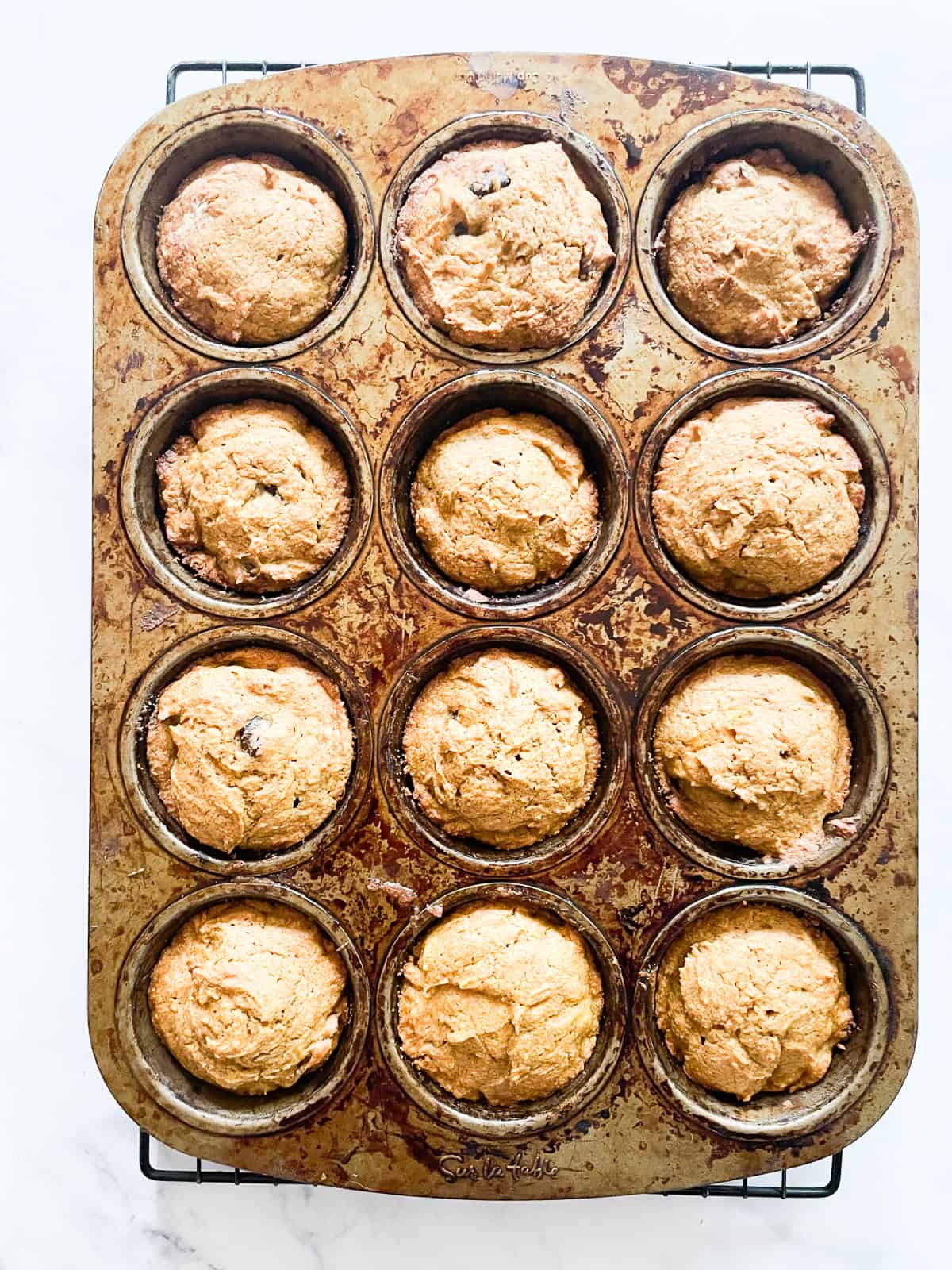 Oat flour pumpkin muffins cool in a muffin tin.