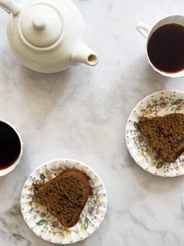 A tea pot, cups of tea, and two slices of pumpkin cake.