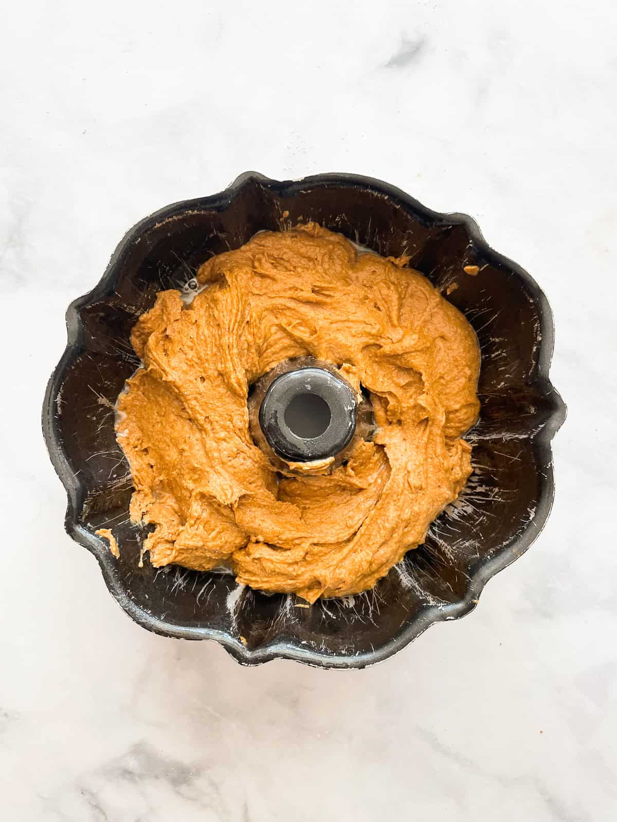 Half of pumpkin cake batter in a bundt pan.