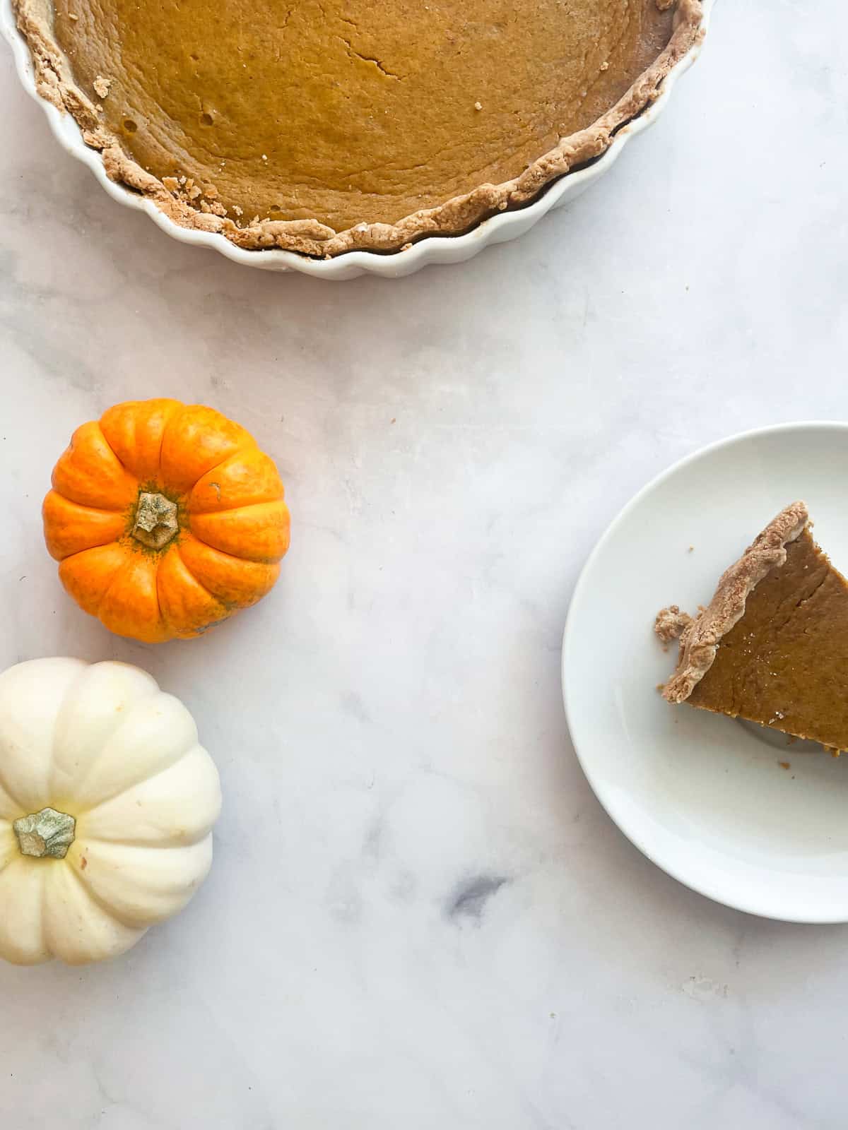 A pumpkin pie slice with small pumpkins and a pie.