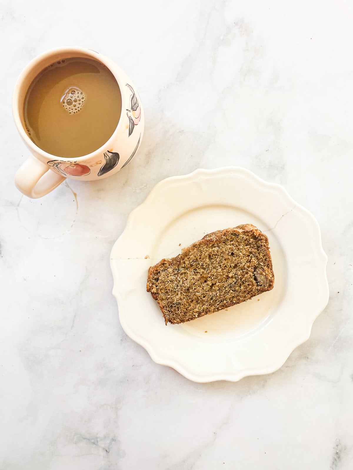 A cup of coffee and a slice of oat flour banana bread on a plate.