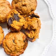 Chocolate chip oat flour pumpkin muffins on a white plate.