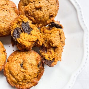 Chocolate chip oat flour pumpkin muffins on a white plate.