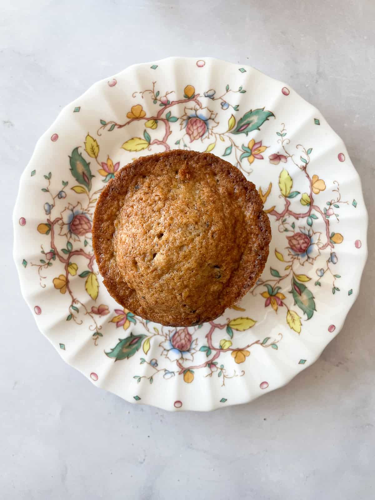 A banana chocolate chunk muffin on a flowered plate.